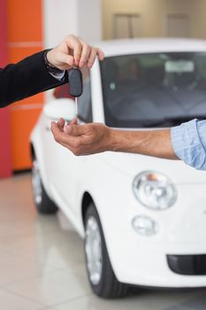 Businessman giving car key to customer at new car showroom