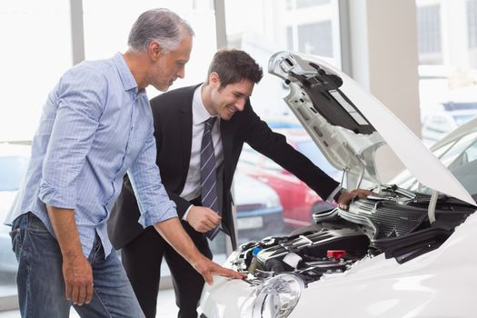 Two men looking at a car engine at new car showroom