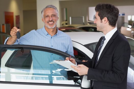 Smiling customer showing his new key at new car showroom