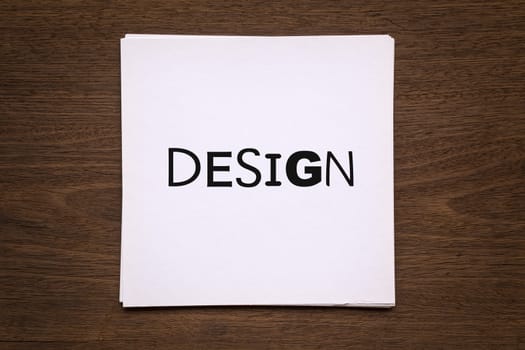 White paper cards with word " Design " putting on natural wood background, vignette and top view image