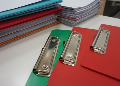 Multi-colored clip board and documents on the desk in office.                              