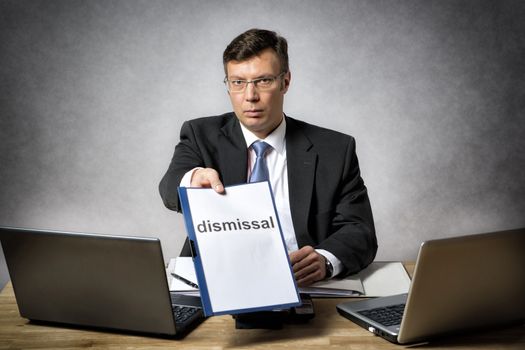 Boss sitting at the desk in office dismiss somebody