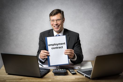 Businessman at the office desk is holding a employment contract