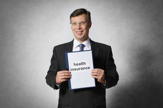 Happy businessman is holding a health insurance contract