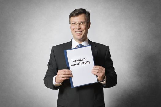 Happy businessman is holding a german health insurance contract