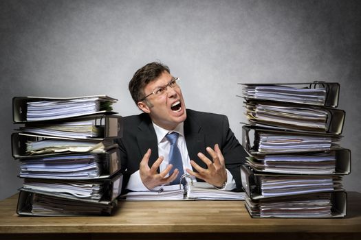 Overworked crying businessman with lot of files on his desk