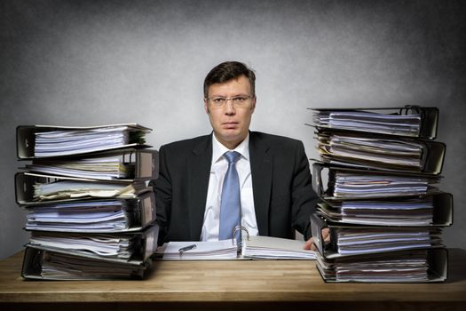 Overworked depressed businessman with lot of files on his desk
