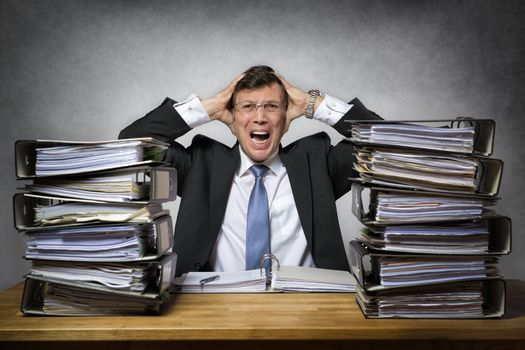 Overworked crying businessman with lot of files on his desk