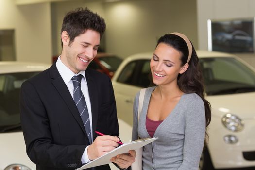 Smiling businessman undersign a car contract at new car showroom