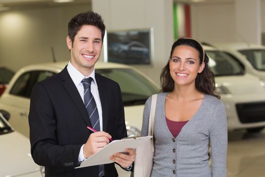 Smiling businessman undersign a car contract at new car showroom