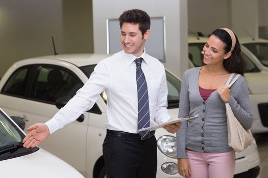 Businessman showing a car to a woman at new car showroom