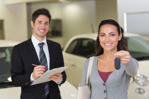 Female driver showing a key after bying a new car at new car showroom