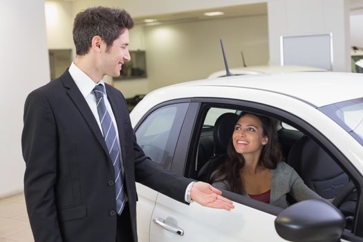 Businessman showing something to a woman at new car showroom