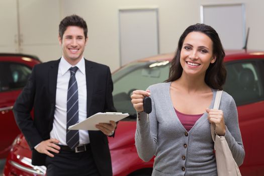 Female driver showing a key after bying a new car at new car showroom