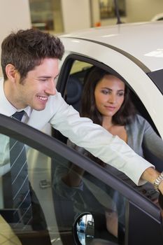 Businessman showing something to his customer at new car showroom