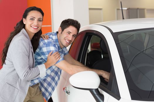 Smiling couple looking inside a car at new car showroom