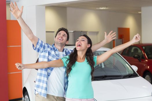 Young couple smiling and cheering at new car showroom
