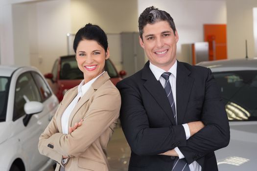 Business team standing with arms crossed at new car showroom