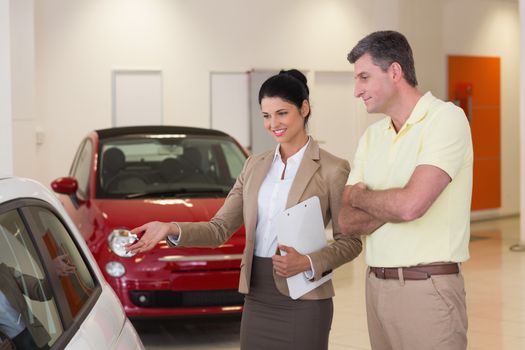 Businesswoman and her client looking at a car at new car showroom