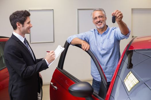 Smiling customer showing his new key at new car showroom