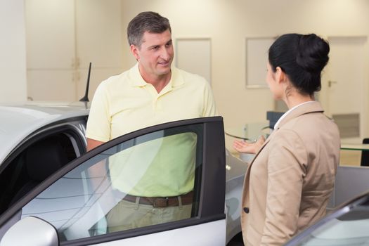 Salesperson talking with her customer at new car showroom