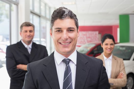 Group of smiling business team standing together at new car showroom