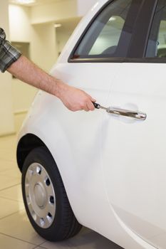 Man opening a car with a key at new car showroom