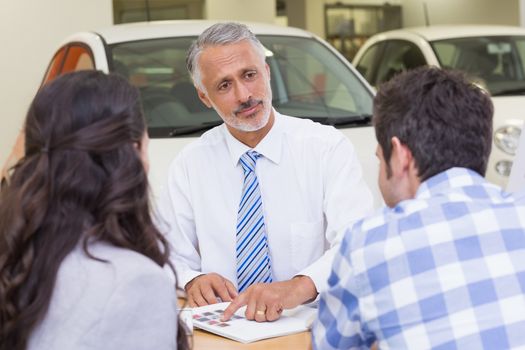 Salesperson pointing something on booklet at new car showroom