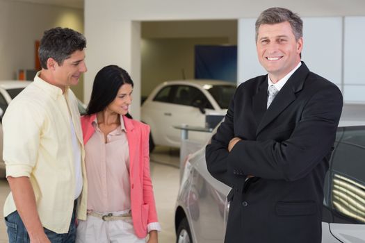 Portrait of a businessman smiling at camera at new car showroom