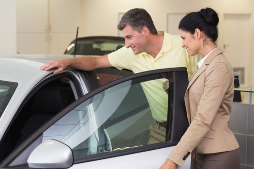 Businesswoman showing a car interior to her customers at new car showroom