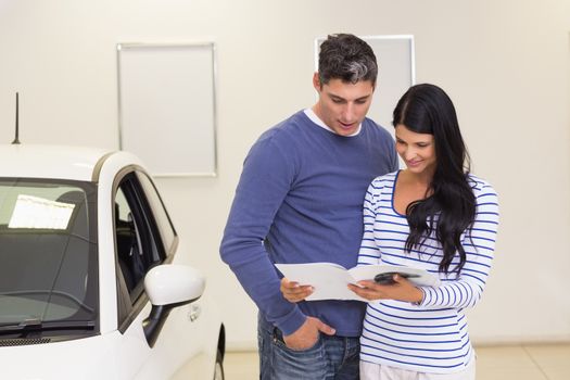 Smiling couple reading a booklet at new car showroom