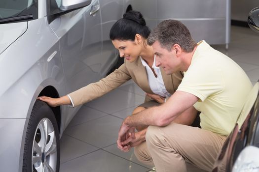 Businesswoman and customer discussing details of car tire at new car showroom