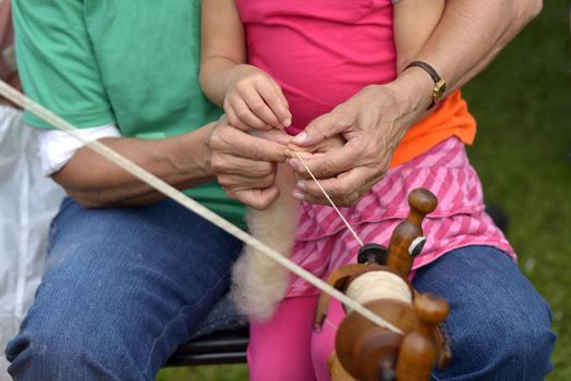 Old lady teaches her little daughter doing handicrafts