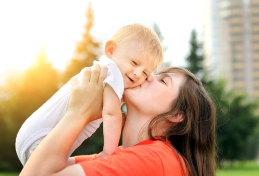 Happy Mother kiss a Little Baby outdoor