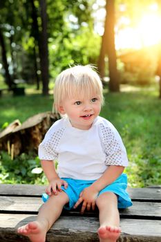 Cheerful Child on the Bench at the Summer Park