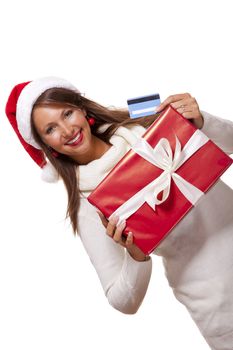 Attractive woman with a lovely smile wearing a red Santa hat holding a big red Christmas gift box and bank card as she celebrates her successful shopping spree