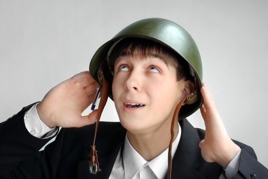 Fearful Teenager in Military Helmet on the Grey Background