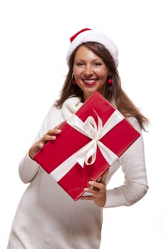 Pretty woman in a festive red Santa hat with a large matching red Christmas gift tied with a ribbon and bow holding it in front of her with a happy smile showing it to the camera, on white