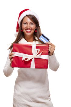 Attractive woman with a lovely smile wearing a red Santa hat holding a big red Christmas gift box and bank card as she celebrates her successful shopping spree