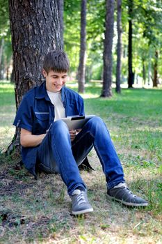 Cheerful Teenager with Tablet Computer in the Summer Park