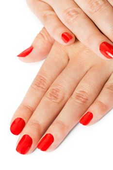 Woman with beautiful manicured red fingernails gracefully crossing her hands to display them to the viewer on a white background in a fashion, glamour and beauty concept