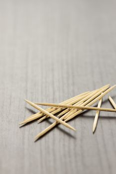 Pile of wooden toothpicks scattered randomly on a grey background for cleaning between the teeth after a meal in a personal hygiene concept