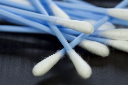 Random pile of blue plastic cotton ear buds for cleaning wax out of the ear in a health and hygiene concept