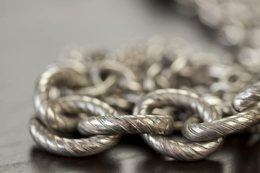 Assorted silver costume jewellery with a jumbled pile of chains with different shaped links, a clear crystal bead and a necklace of round silver beads with focus to the chains