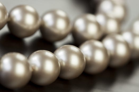 String of shiny grey beads winding through the frame in a close up view of fashion jewellery with selective focus to two beads