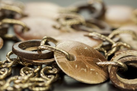 Scratched and tarnished old silver jewellery with two flat discs flanking a ring suspended on an oval link chain, close up view on a grey background