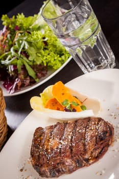 Delicious trimmed lean portion of thick grilled beef steak with seasoning served on a white plate, close up with shallow dof