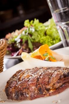 Delicious trimmed lean portion of thick grilled beef steak with seasoning served on a white plate, close up with shallow dof