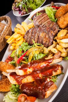 Wholesome platter of mixed meats including grilled steak, crispy crumbed chicken and beef on a bed of fresh leafy green mixed salad served with French fries and chutney or BBQ sauce in a dish