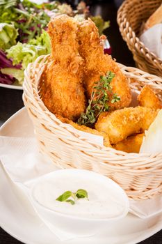 Crisp crunchy golden chicken legs and wings deep fried in bread crumbs and served with a bowl of dip in a wicker basket for a delicious appetizer